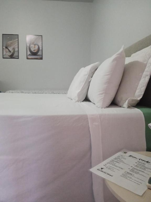 a white bed with white pillows on top of it at Jardim Primavera in Palmas