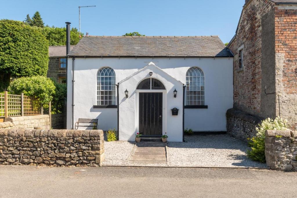 a white house with a door and a stone wall at 2 Bed in Matlock oc-dcocc in Two Dales