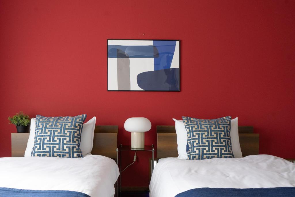 two beds in a room with a red wall at cozy 3rd stay in Okayama