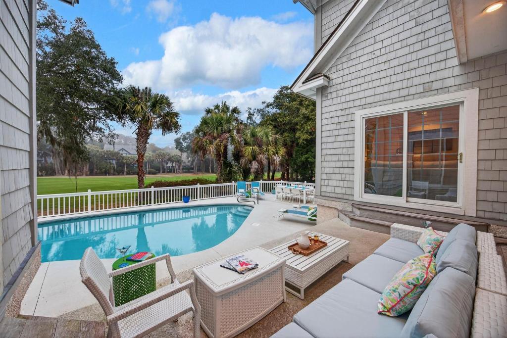 a swimming pool with a couch and chairs next to a house at GE317: 317 Glen Eagle in Kiawah Island