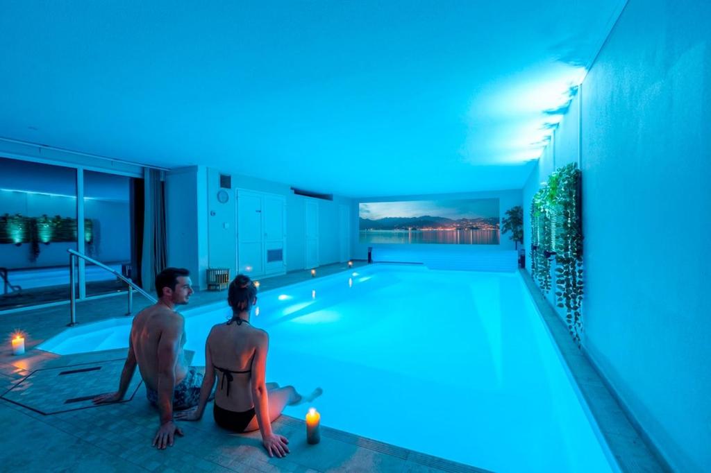 two people sitting next to a swimming pool at night at Romantic 4-star suite with private heated pool in Gimbrett