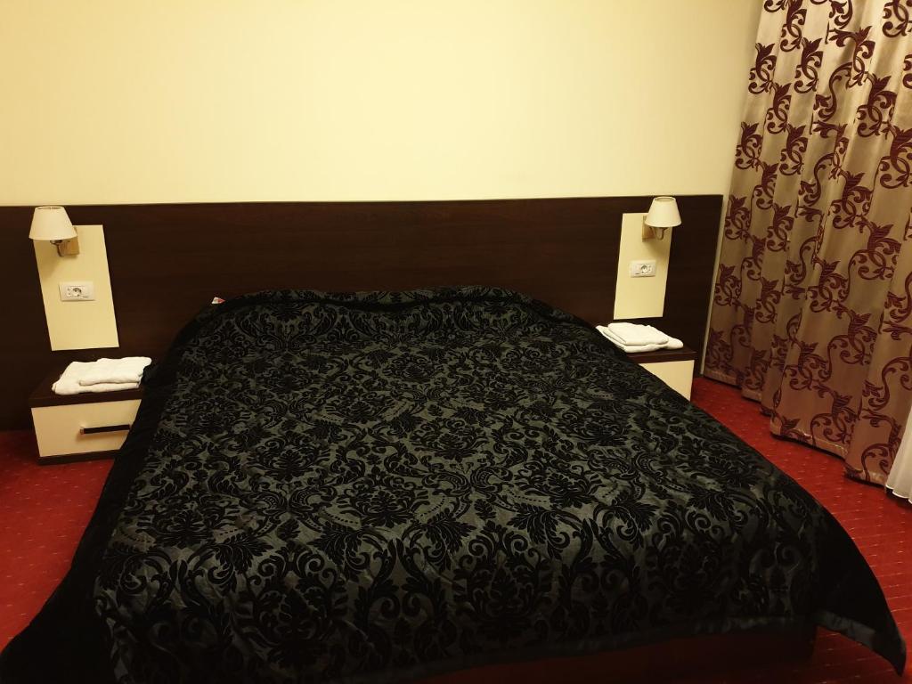 ein Schlafzimmer mit einem schwarzen Bett und zwei Nachttischen in der Unterkunft Casa Marly in Caracal