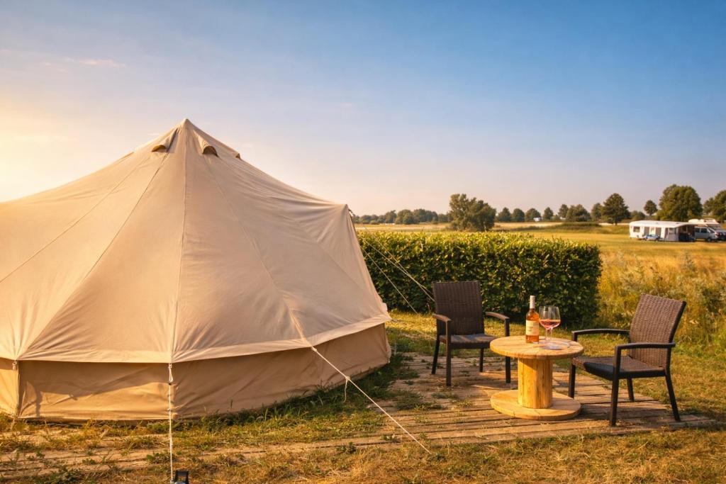 a tent with chairs and a table in a field at Bell Tent aan de haven in Heerewaarden