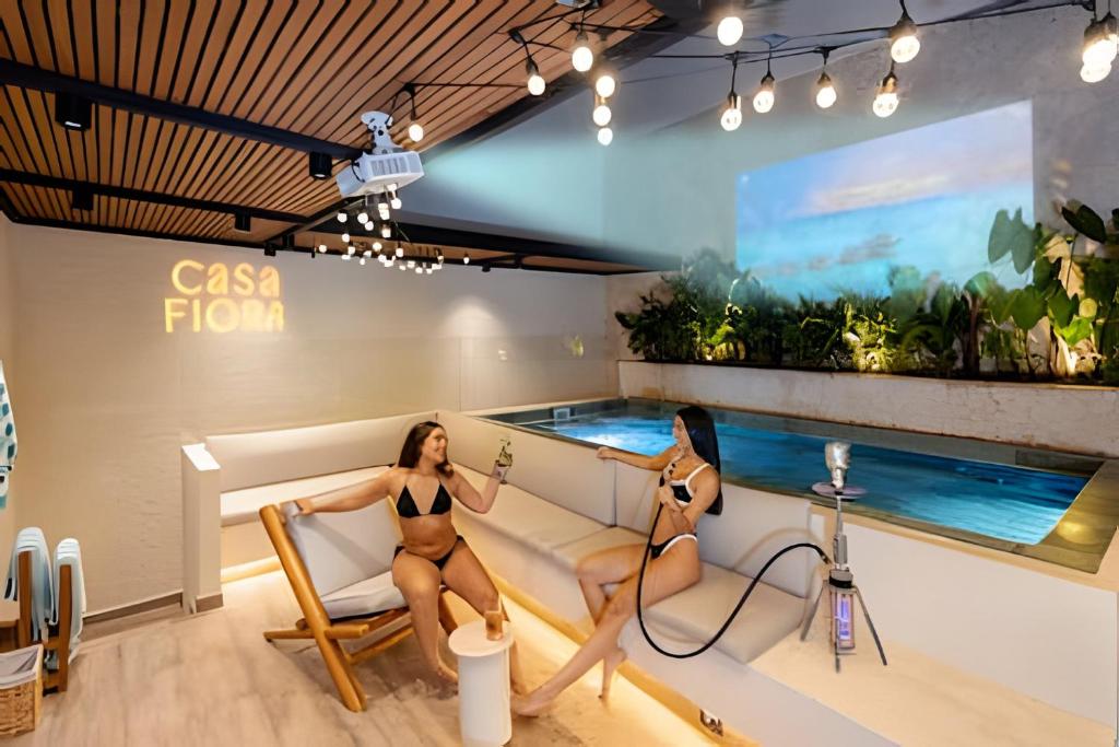 a woman sitting on a couch next to a swimming pool at 2Luxury Provenza: Htd Pool, Jacuzzi, BBQ, Pool in Medellín