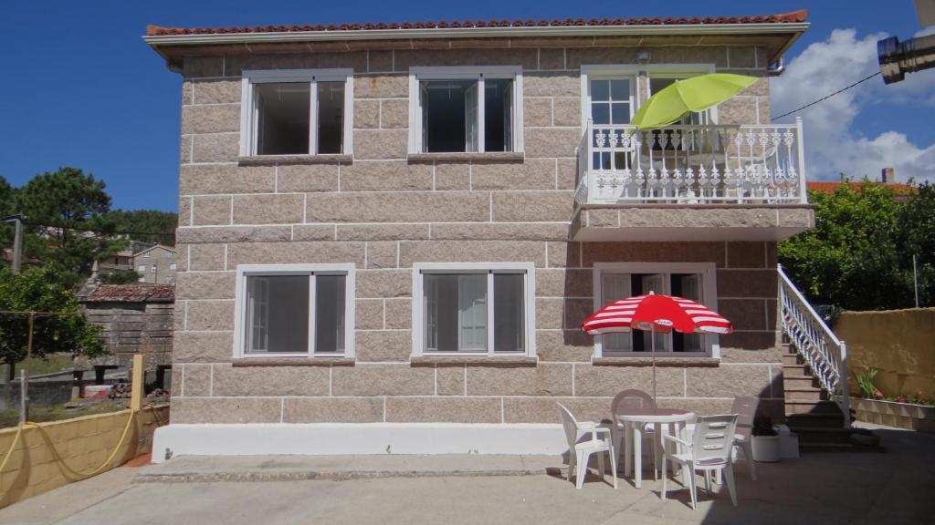 a house with a table and an umbrella on the balcony at Casa Bruna Baixo A Apartamento a 800 m de la playa in Lariño