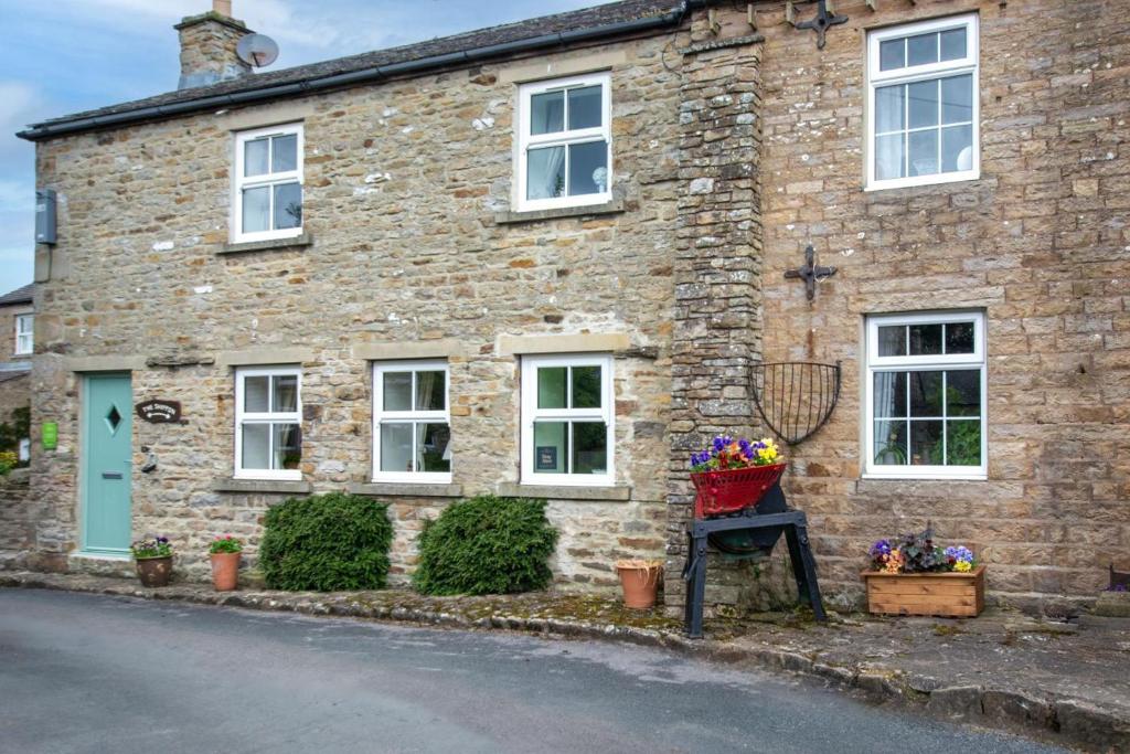 a brick house with a basket of flowers in front of it at 2 Bed in Leyburn oc-ds902 in Askrigg