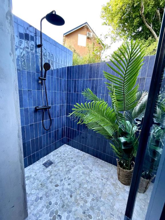 a bathroom with a blue tiled shower with a plant at CASA M Peaceful haven with pool in Îlet à Christophe