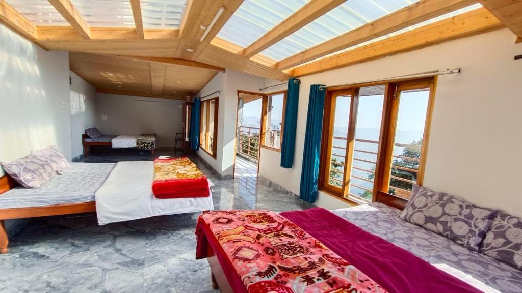 a bedroom with two beds and a large window at The Hostelers Homestay Shimla - Near ISBT, Bypass MC Parking and HPU in Shimla