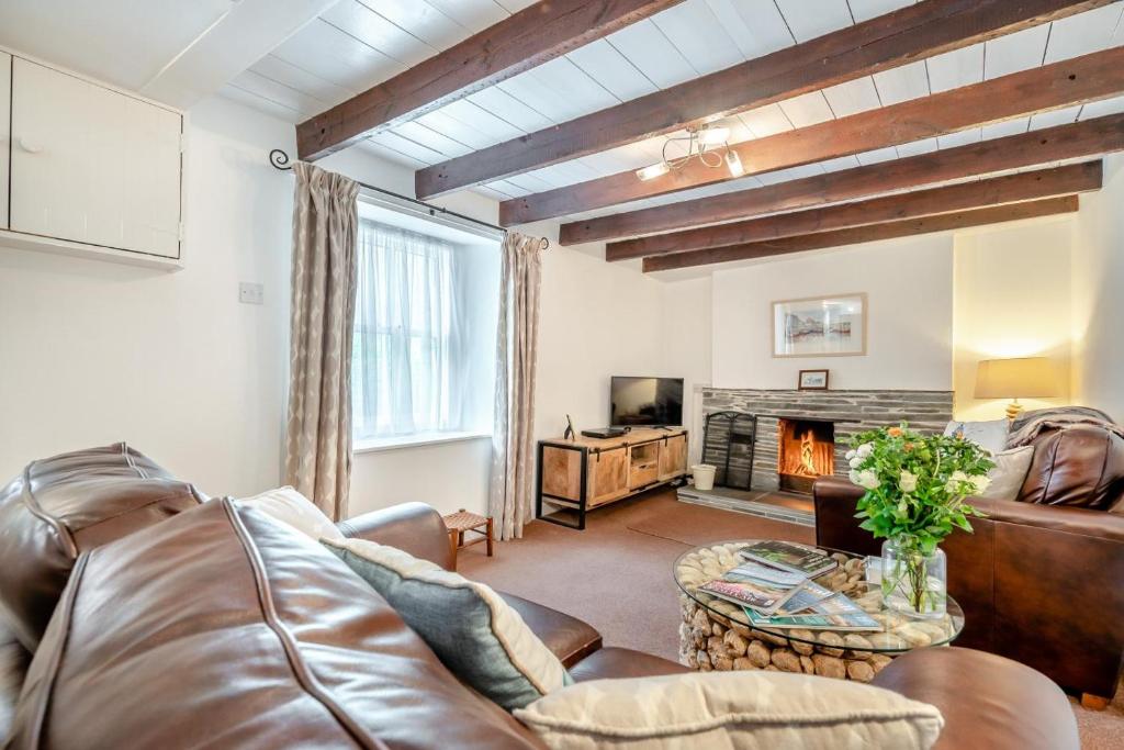 a living room with a leather couch and a fireplace at 2 Bed in Bodmin oc-p00429 in Saint Teath