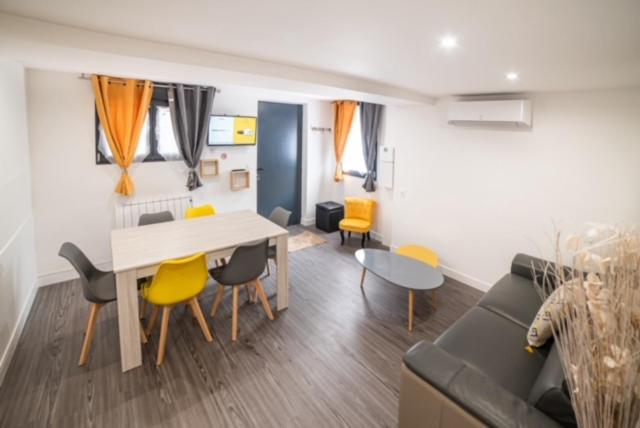 a living room with a couch and a table and chairs at Appartement Sun GroupamaLyon Eurexpo in Meyzieu