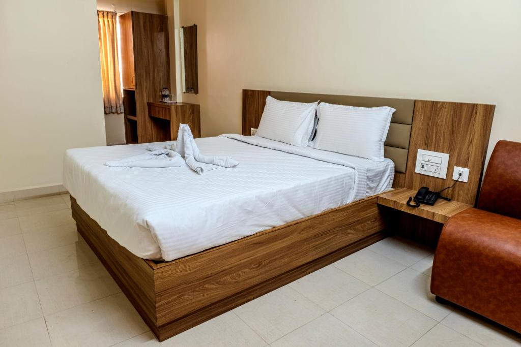 a bedroom with a large bed with white sheets at Hotel M S Chola in Chennai