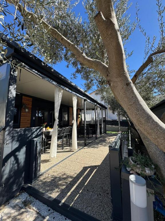a building with white curtains on it next to a tree at Mobile Home Clelia in Sveti Petar