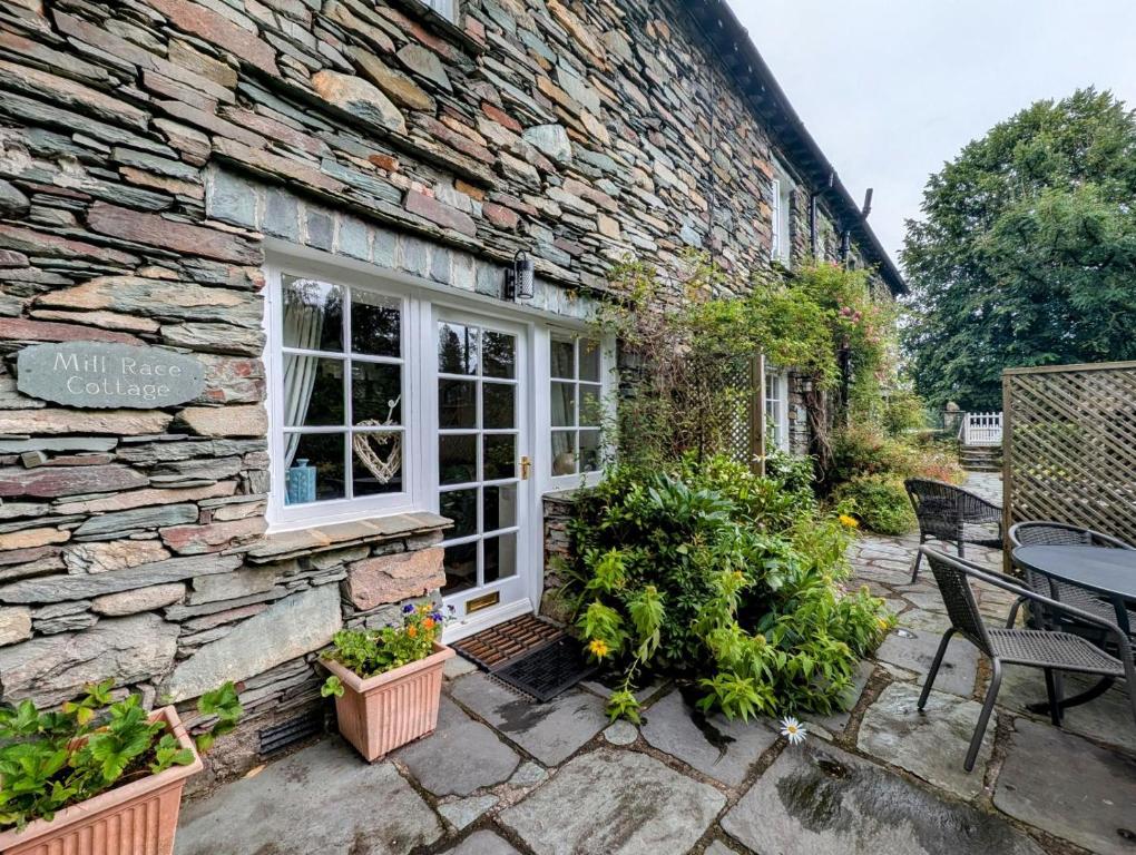 a stone house with a patio and a stone wall at 2 Bed in Elterwater oc-gl053 in Chapel Stile
