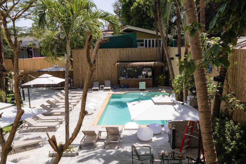 an outdoor swimming pool with lounge chairs and umbrellas at Aloha Tropicana Samui in Chaweng