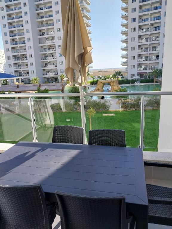 a blue table with chairs and an umbrella on a balcony at Pool View Apartment with Hotel Facilities in Iskele