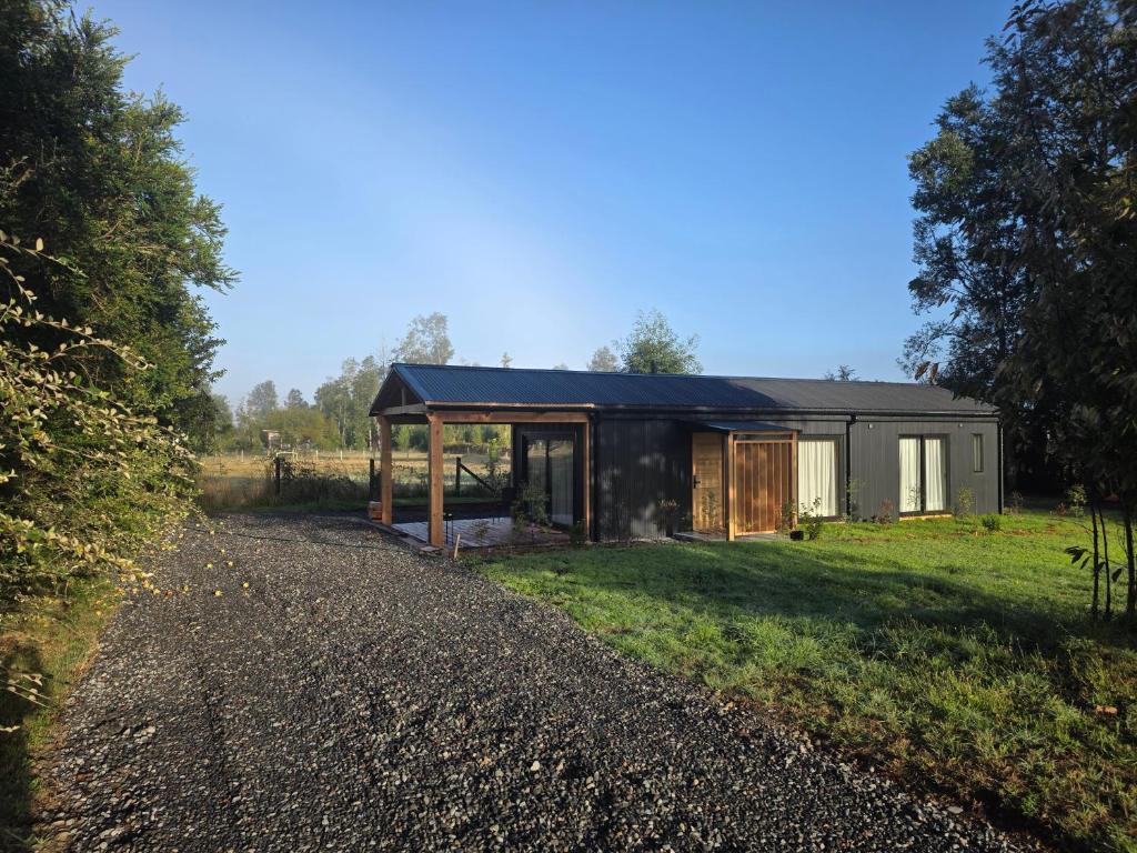 a house with a black roof and a gravel driveway at Estancia del Sol in Putúe