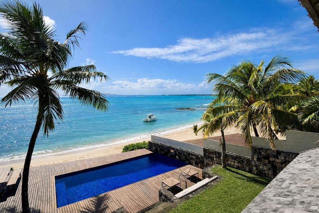 a house with a swimming pool next to the beach at Villa Canonniers - Pieds dans l'eau à Grand Baie in Pointe aux Canonniers