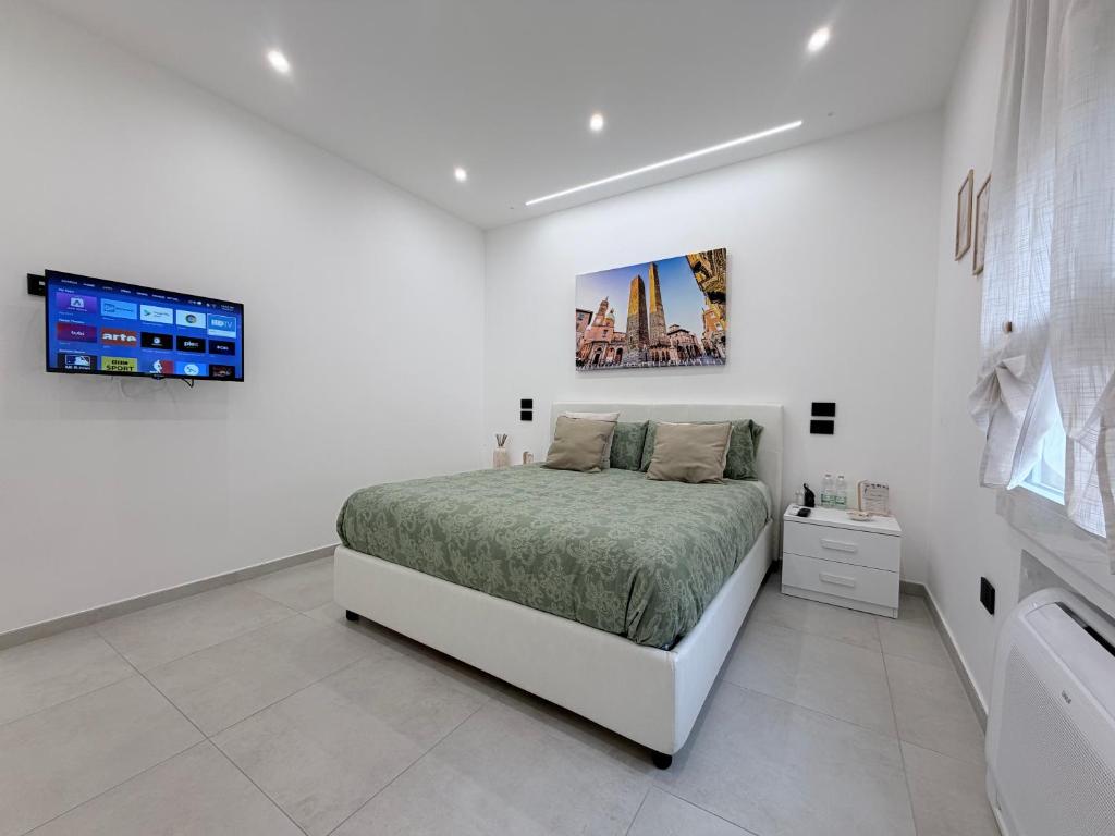 a white bedroom with a bed and a tv at B&B Sabò in Bologna