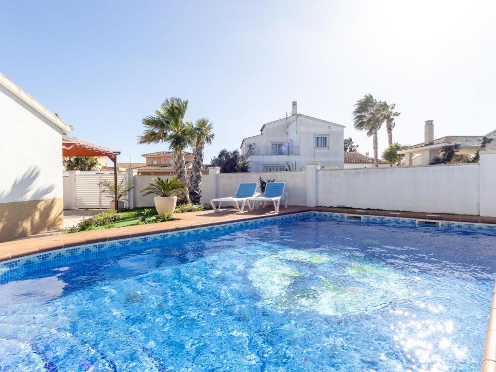 a large swimming pool with two blue chairs in a backyard at Holiday Home Estrella by Interhome in Riumar