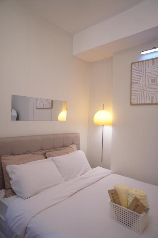 a bedroom with a white bed with a basket on it at The Storeys - Mesaverte Residences CDO in Pontud