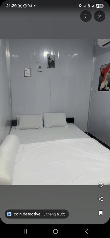 a white bed in a white room with avertisement at Home 100k in Vị Thanh
