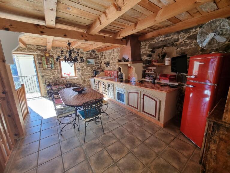 a kitchen with a table and a red refrigerator at Maison Le Rêve in Evisa