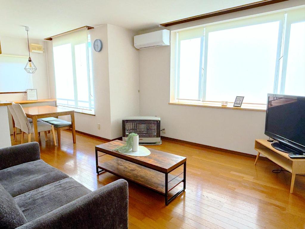 a living room with a couch and a table at Olive retreat Sapporo 札幌市南区 一軒家の1フロア貸切 5名まで 2ベッドルーム 無料駐車場 登山 スキー場への好アクセス in Sapporo