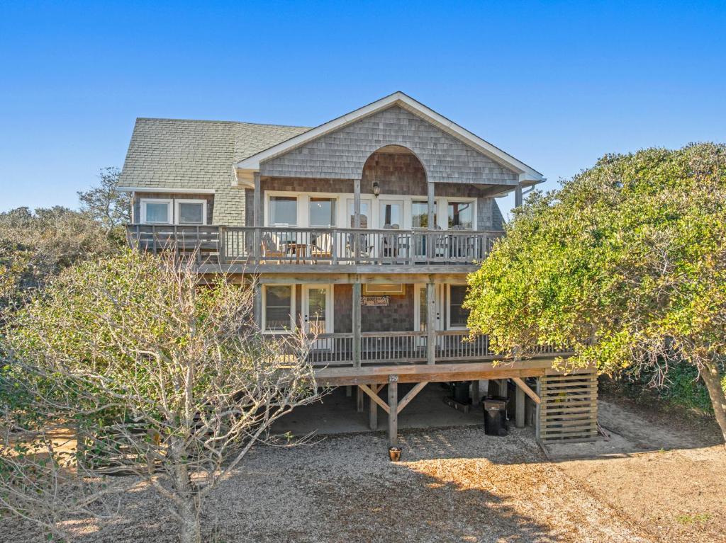 a large house with a large deck and trees at Boots to Beach in Duck