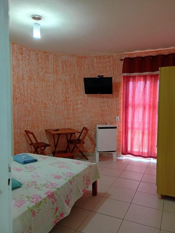 a room with a table and a television on the wall at Pousada Real in Itamonte