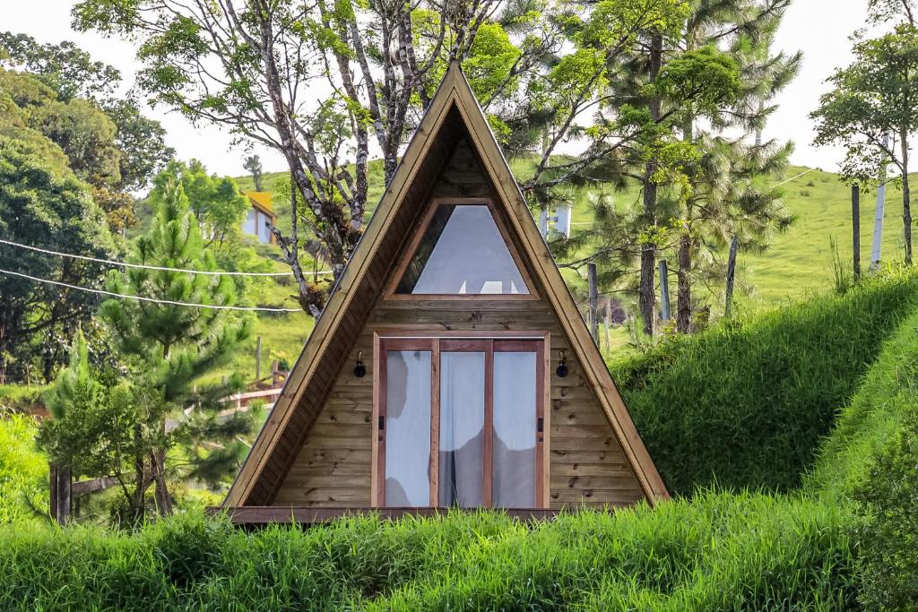 a triangular house with a door in the grass at Chalé Serra Furada - vista única da Serra Furada in Grão Pará