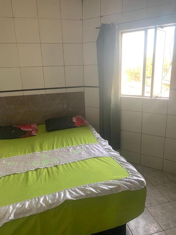 a green bed in a room with a window at Soberano hotel in Arapiraca