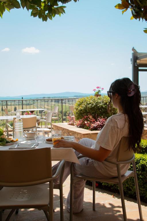 a woman sitting at a table looking out at the ocean at Terra d'Ombra Bed&Breakfast in San Gimignano
