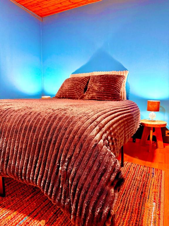 a bedroom with a large bed with a blue wall at La Ferme des Roses in Tournai