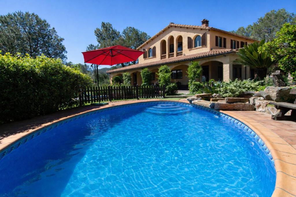a swimming pool with an umbrella in front of a house at Catalunya Casas Peaceful Perfection , only 30km from Barcelona! in Vacarisas