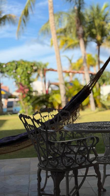 a black bench sitting next to a table with palm trees at Pousada Vila Assu in Ceará-Mirim