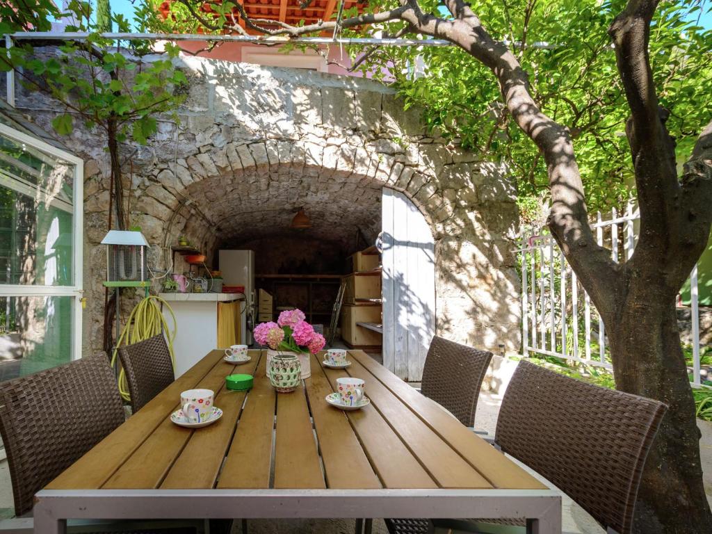 - une table en bois avec des tasses et des fleurs sur la terrasse dans l'établissement Lovely Mediterranean home near the beach, à Cavtat