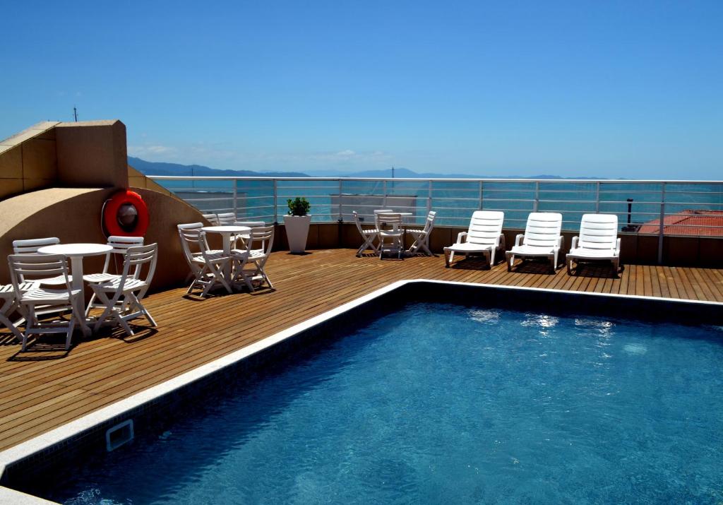 una terraza con piscina, sillas, mesa y sillas en Luisa Palace Hotel en Florianópolis