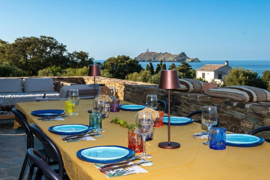 a table with plates and glasses on top of a table at Villa CAMILLE in Ersa