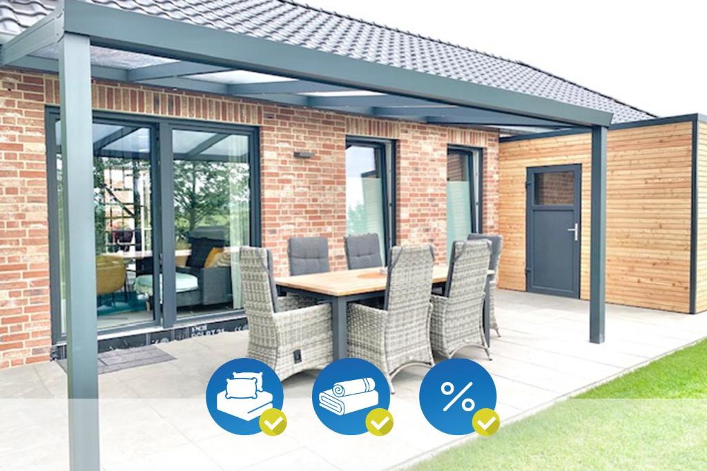 a pergola with a table and chairs on a patio at Idyllisches Ferienhaus mit Spielzimmer und Garten in Sehestedt