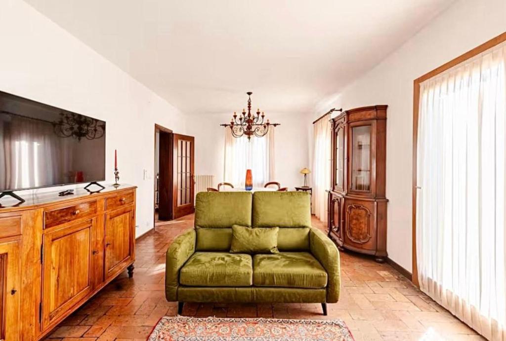 a living room with a green chair and a television at "Venetian Elegance Villa" - near Venice historic center in Mira