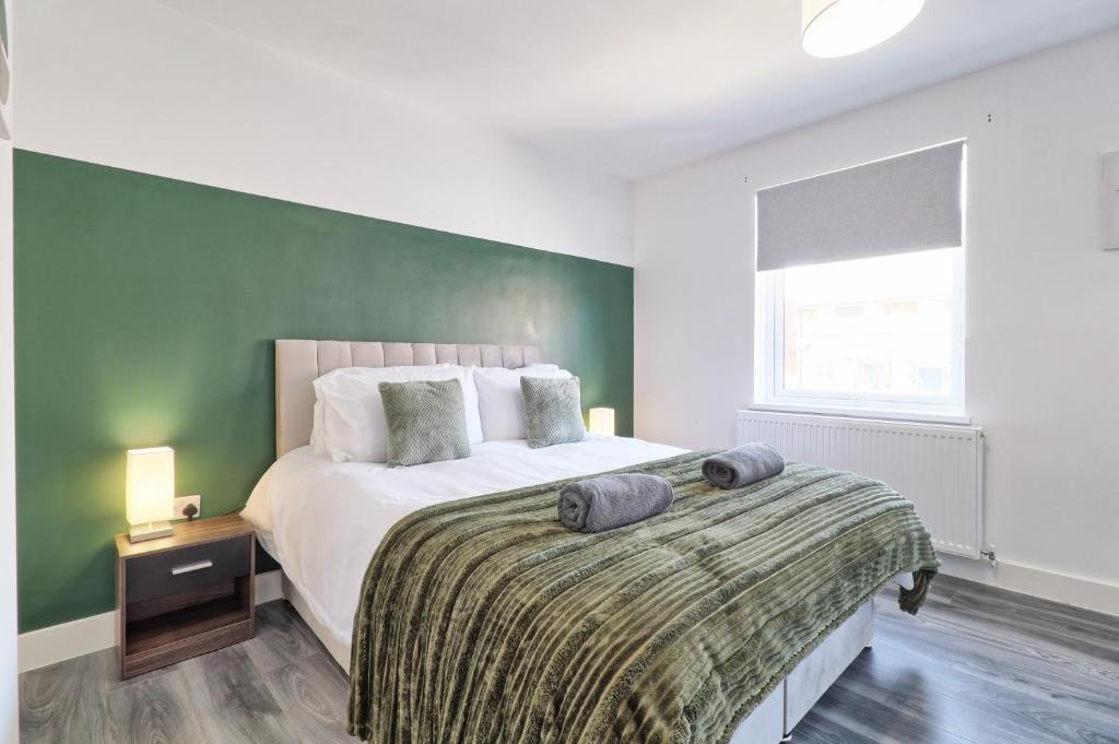 a bedroom with a large bed with a green wall at Colchester 4BR Home, Sleeps 8, Fast WiFi, Perfect for Contractors in Hythe