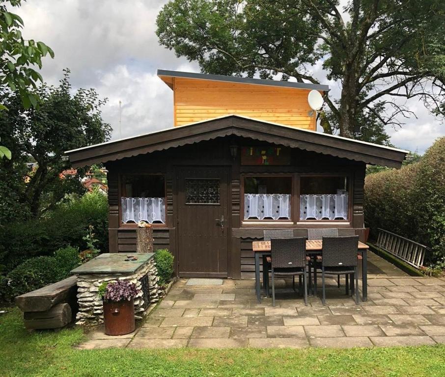 a small cabin with a table and chairs in a yard at Ferienhaus am Jakobsberg in Königsfeld