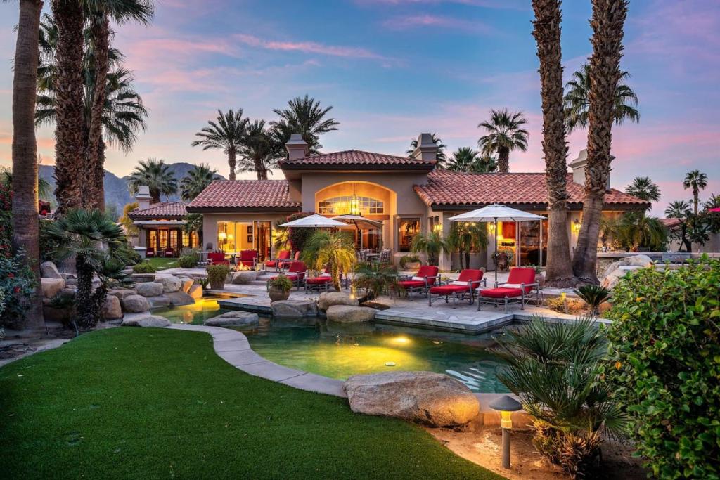 a home with a swimming pool and palm trees at Villa Merion at PGA West | Grand Tuscan Estate in La Quinta