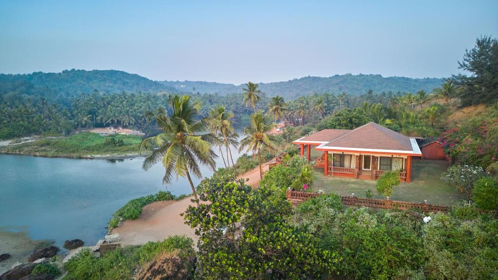 a house on a hill next to a body of water at SaffronStays The Devrai by the Sea in Bhogwe