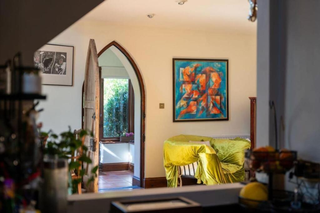 a living room with a yellow couch and an archway at Church conversion, Private garden, Parking in Cuckfield
