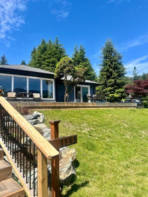 a house with a wooden rail and a yard at Captain Cottage in Bowen Island