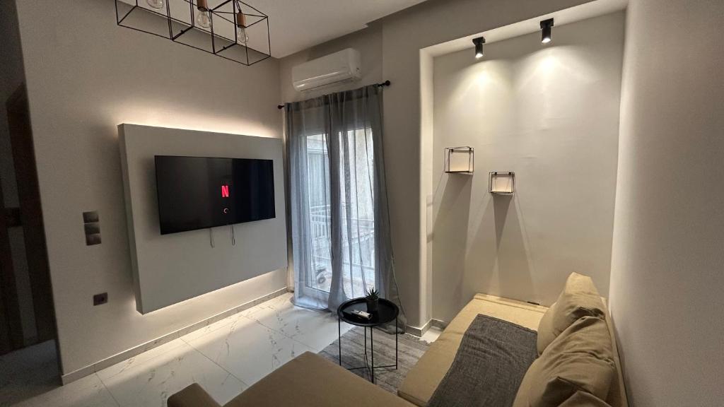a living room with a couch and a tv on a wall at The Little House Lamia - Fresh Central Apartment in Lamía