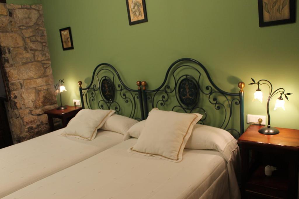 a green bedroom with a bed with two pillows at Rodiles Rural Apartamentos in Selorio