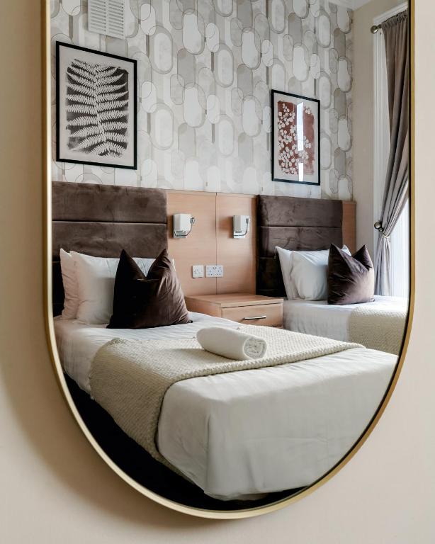 a mirror reflecting a bedroom with two beds at Mina Hotel by PLI in London