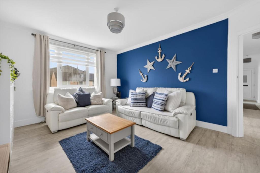 a living room with two couches and a blue wall at Troon Golf by the Sea in Troon